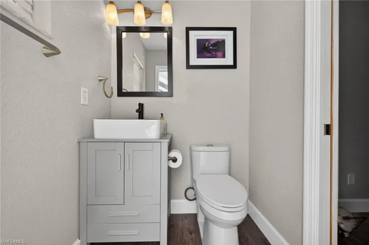 Half bath with vanity and dark wood-type flooring