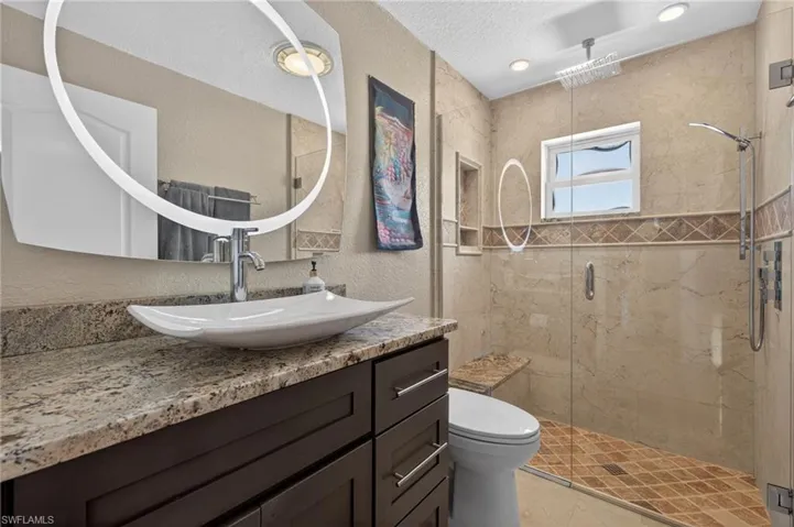 Bathroom with a shower stall, vanity, a textured wall, and a textured ceiling