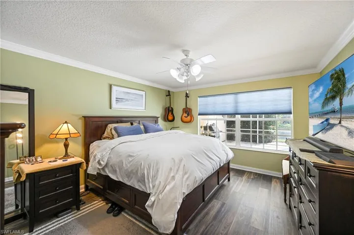 Bedroom featuring ornamental molding, dark wood finished floors, a textured ceiling, and ceiling fan