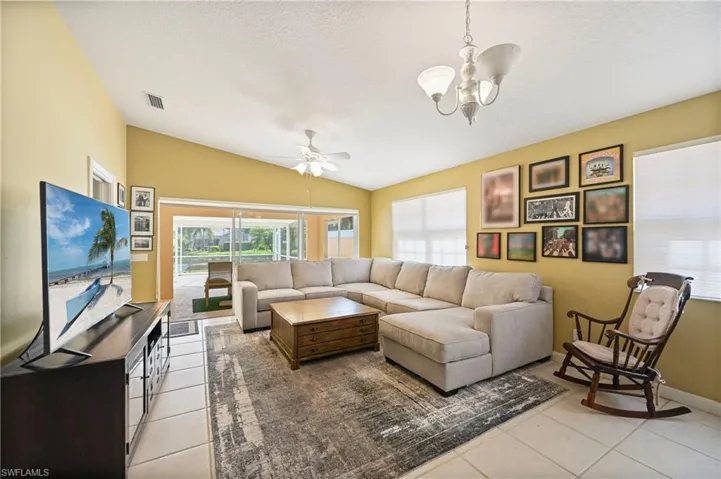 Living area with light tile patterned floors, vaulted ceiling, ceiling fan, and a textured ceiling