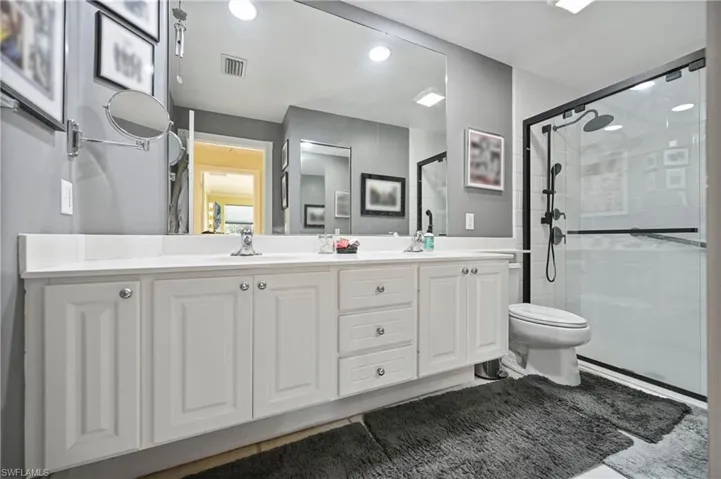 Full bathroom with double vanity, a shower stall, tile patterned flooring, and recessed lighting