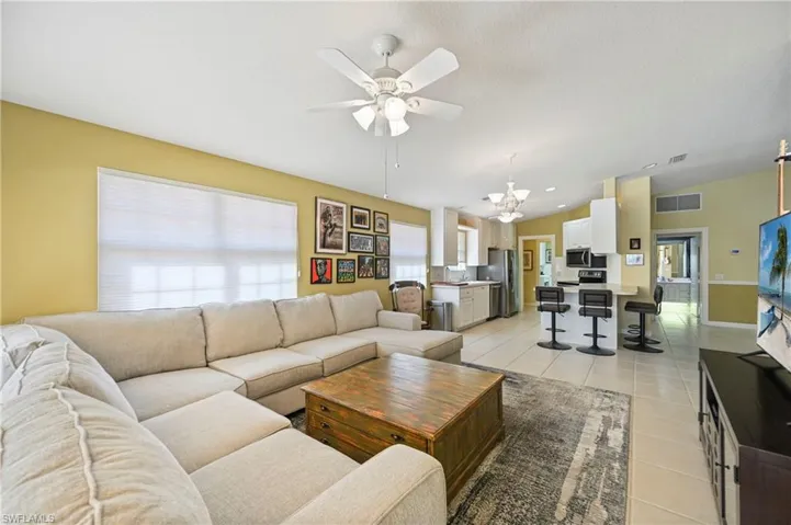 Living room with light tile patterned floors, vaulted ceiling, a ceiling fan, and a chandelier