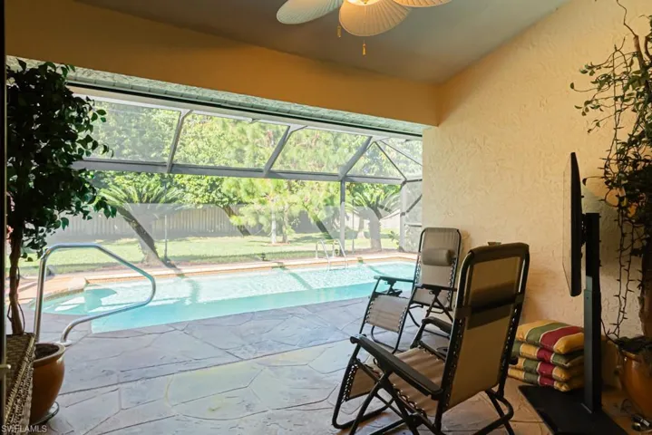 Swimming pool featuring a sunroom, glass enclosure, a ceiling fan, and a patio area