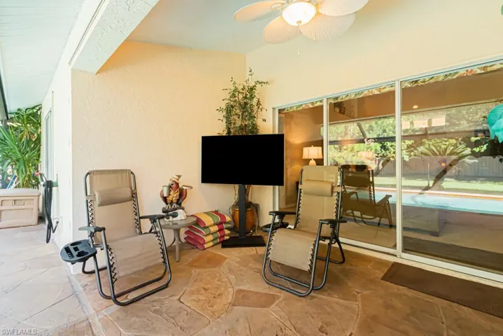 Sitting room with stone tile flooring, a ceiling fan, and a textured wall