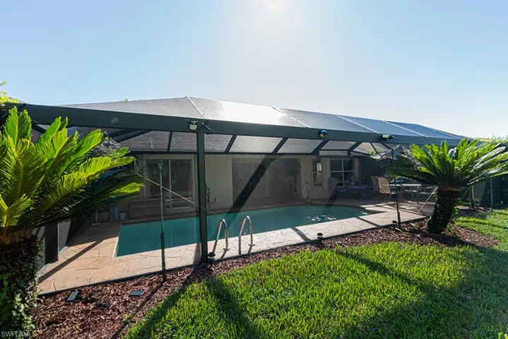 Back of property with glass enclosure, a patio area, a sunroom, and an outdoor pool