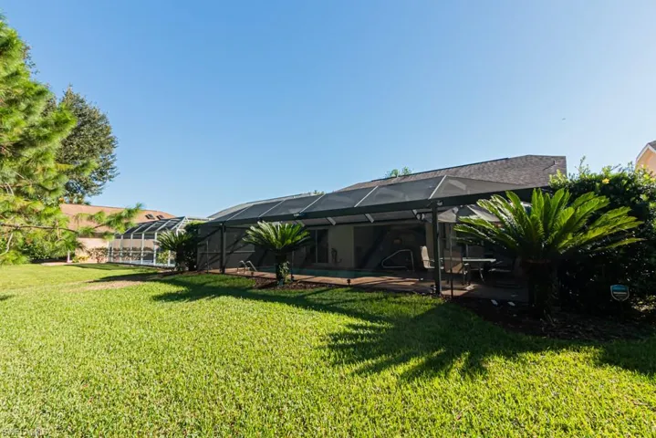 View of green lawn featuring glass enclosure, a patio area, a sunroom, and an outdoor pool