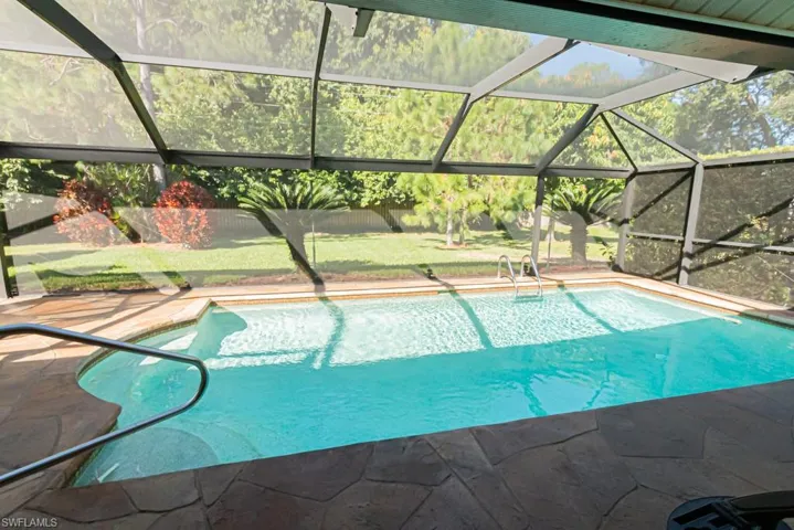 Swimming pool with glass enclosure, a sunroom, and a lawn