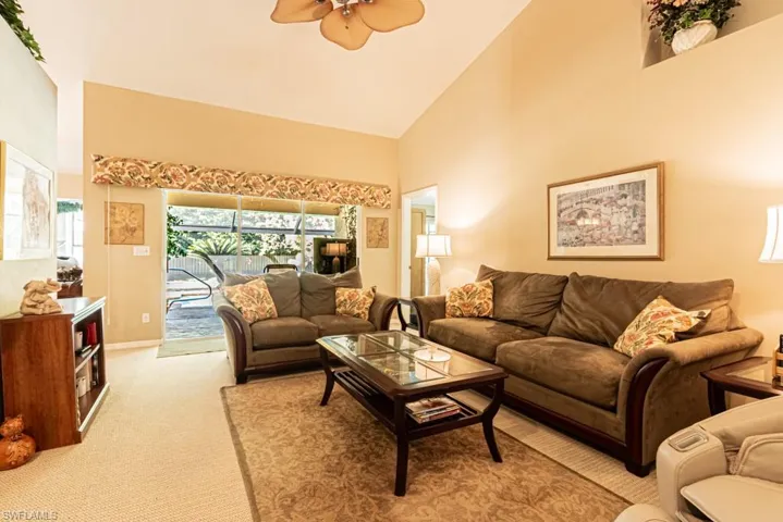 Living room with light colored carpet, high vaulted ceiling, and ceiling fan