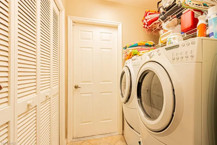 Laundry area with light tile patterned floors and washer and clothes dryer