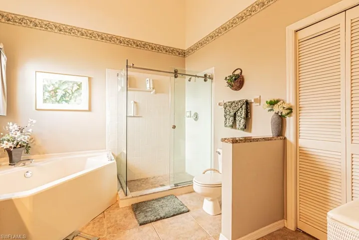 Full bath featuring a closet, a garden tub, a stall shower, and tile patterned floors