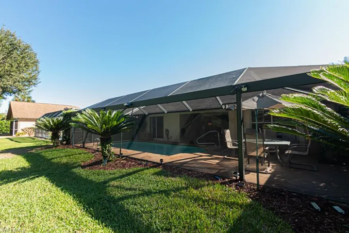 Back of property with glass enclosure, a lawn, a sunroom, an outdoor pool, and a patio area
