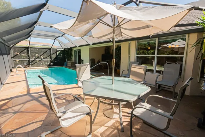 Outdoor pool with a sunroom, a patio, glass enclosure, and outdoor dining space