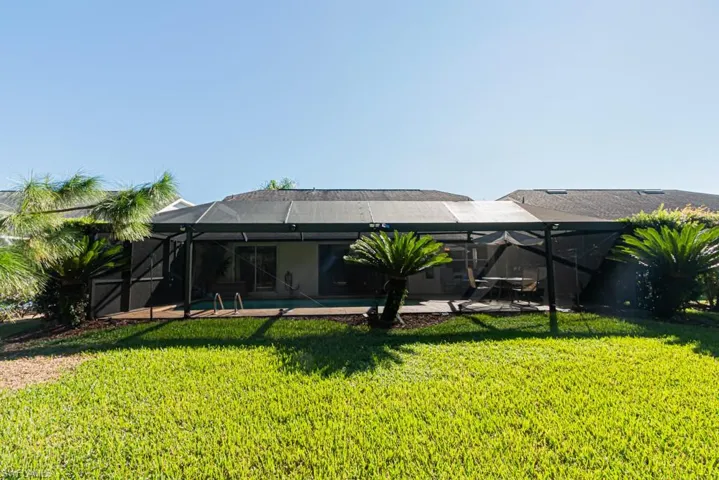 Rear view of property featuring a lanai, an outdoor pool, a yard, and a patio