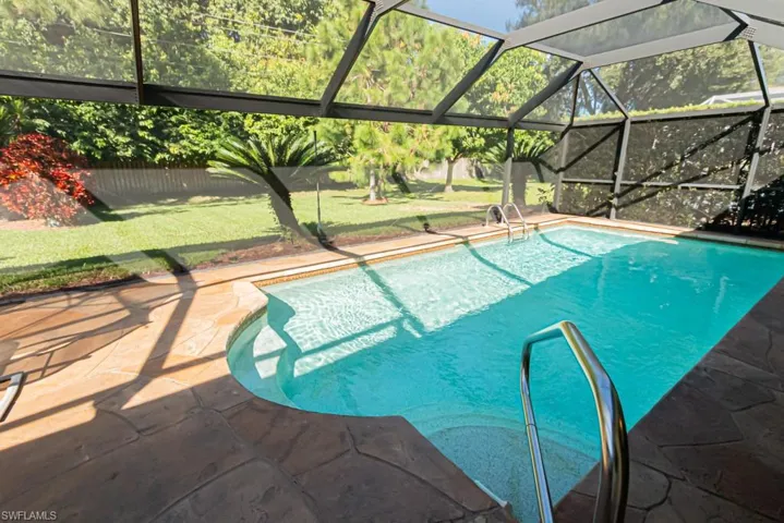 Outdoor pool featuring glass enclosure, a lawn, and a sunroom