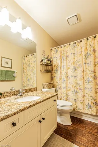 Bathroom featuring vanity, dark wood-style floors, and shower / bathtub combination with curtain