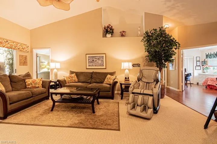 Living area with plenty of natural light, ceiling fan, carpet floors, and high vaulted ceiling