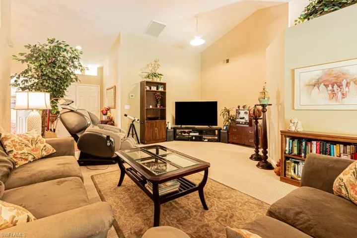 Carpeted living area with high vaulted ceiling