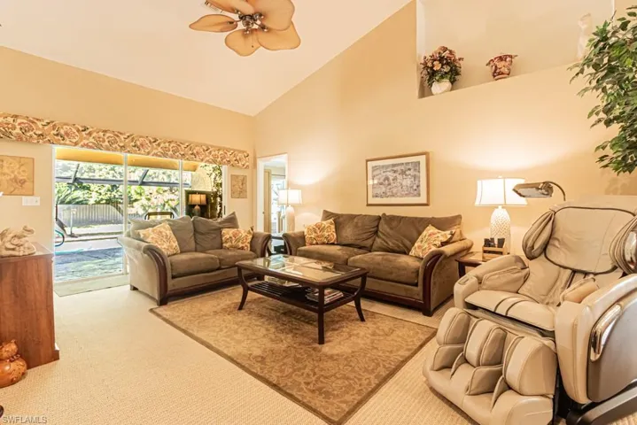 Living room with high vaulted ceiling, carpet, a ceiling fan, and a sunroom