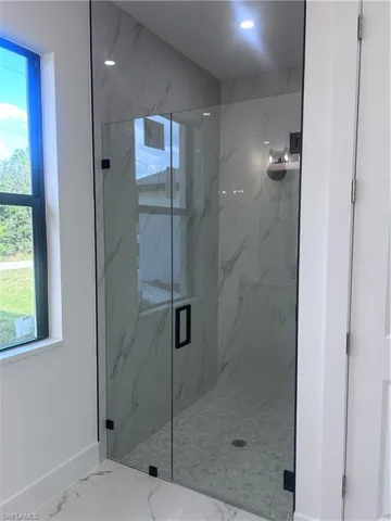 Full bathroom with marble look tile flooring and a marble finish shower