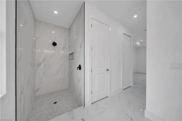 Bathroom featuring recessed lighting, light marble finish floors, and a marble finish shower