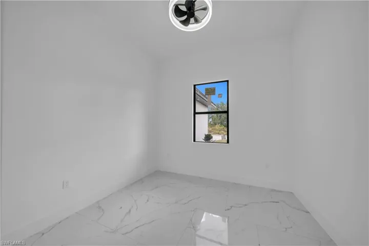 Unfurnished room featuring light marble finish floors and baseboards