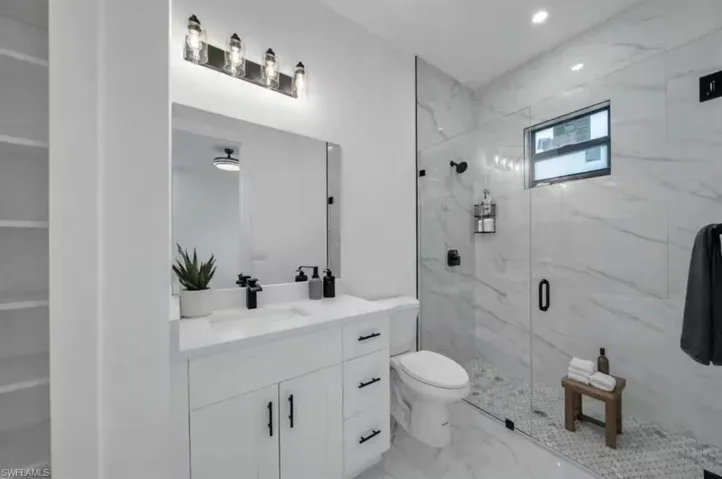 Bathroom with vanity, light marble finish floors, a marble finish shower, and recessed lighting