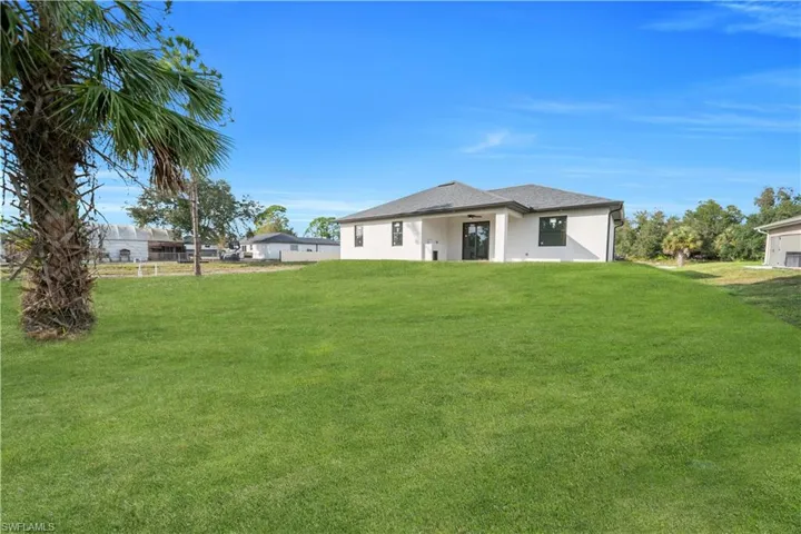 Rear view of property with a lawn and stucco siding