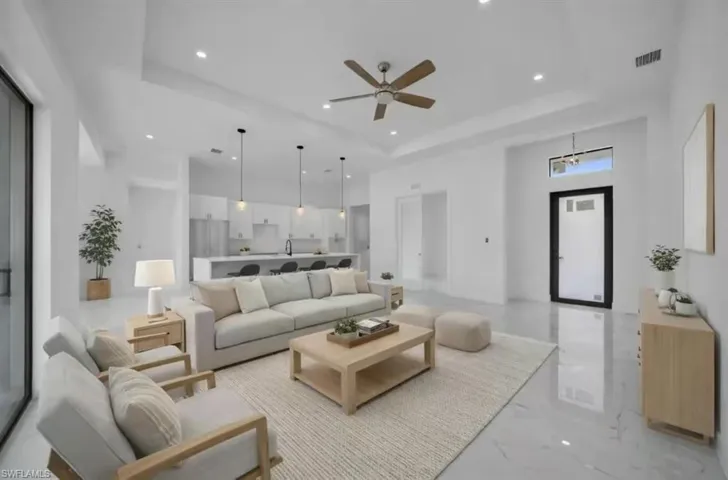Living area featuring a tray ceiling, recessed lighting, a ceiling fan, and a high ceiling