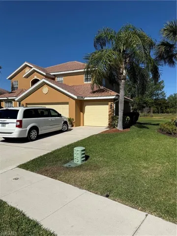 View of front of home with a front yard, an attached garage, stucco siding, concrete driveway, and a tiled roof