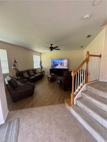 Living room featuring visible vents, a textured ceiling, stairway, tile patterned flooring, and ceiling fan