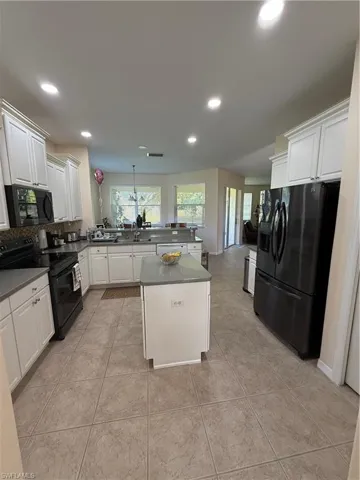 Kitchen featuring stove, a peninsula, fridge, and light tile patterned flooring