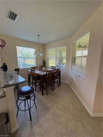 Dining area featuring light tile patterned floors, visible vents, baseboards, and a textured ceiling