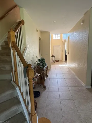 Corridor with arched walkways, tile patterned flooring, stairs, and a textured wall