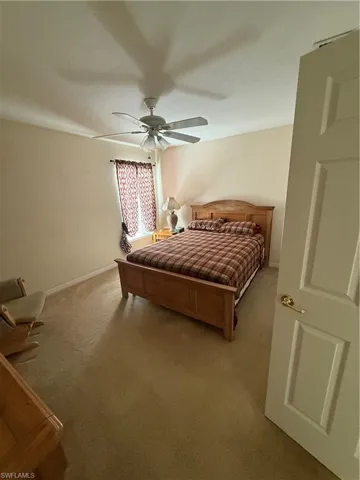 Bedroom featuring baseboards, light colored carpet, and ceiling fan