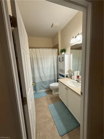Full bathroom featuring visible vents, curtained shower, toilet, tile patterned floors, and vanity