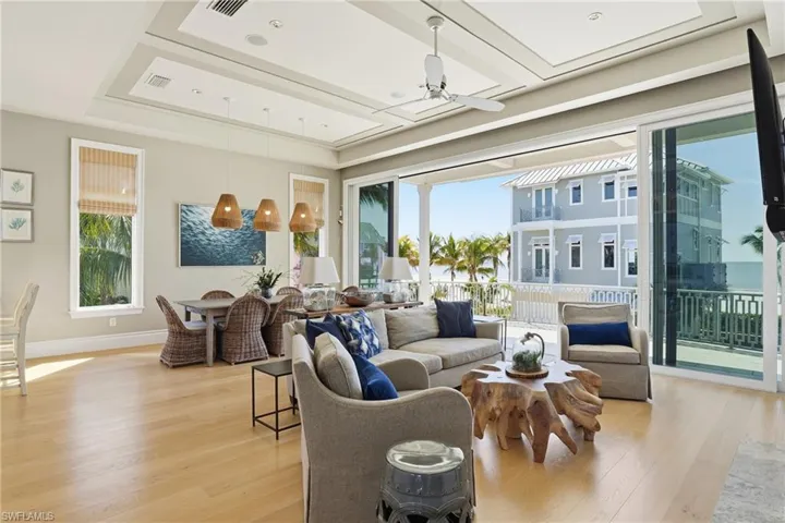 Living area featuring ceiling fan, light wood-style flooring, and a raised ceiling