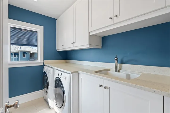 Laundry area with baseboards, a sink, cabinet space, and washer and clothes dryer