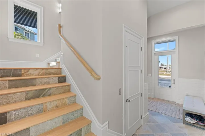 Stairs featuring a wainscoted wall and stone finish flooring