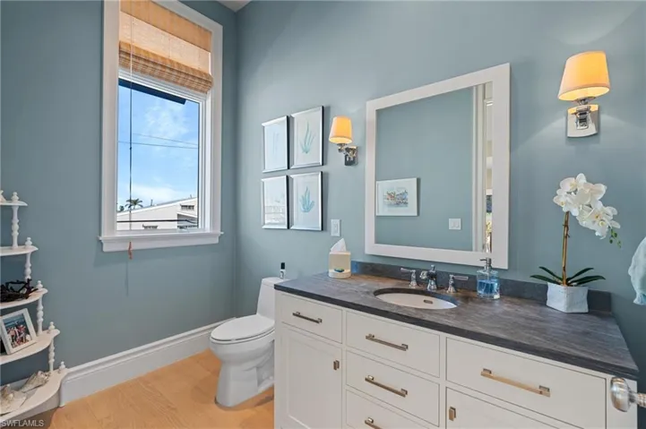Half bath featuring toilet, wood finished floors, vanity, and baseboards