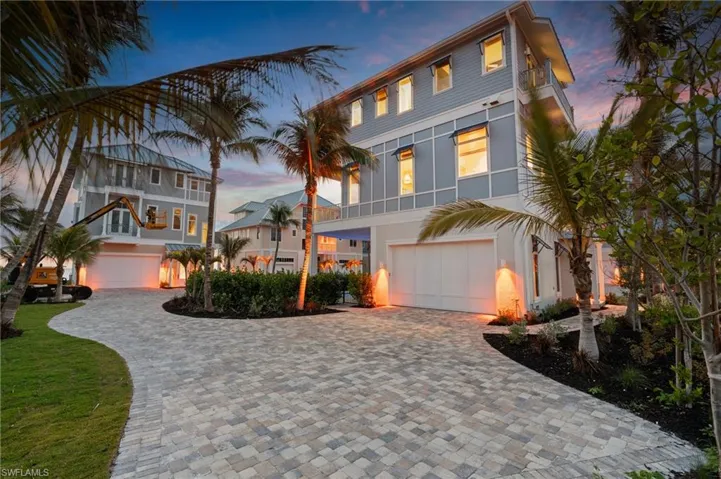 Coastal home with a garage, stucco siding, and decorative driveway
