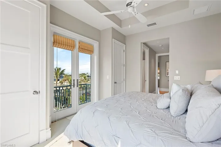 Bedroom featuring access to outside, visible vents, a tray ceiling, ceiling fan, and carpet