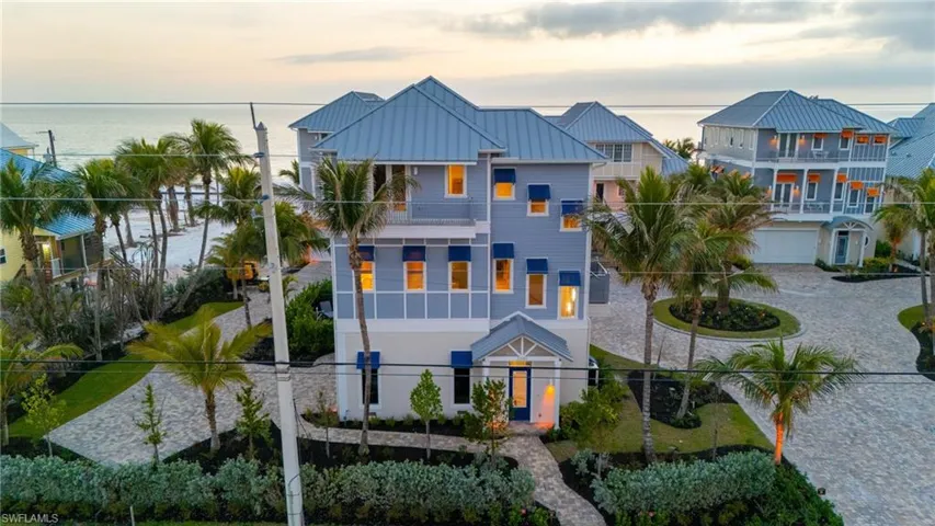 View of front of property featuring a water view, a residential view, curved driveway, a standing seam roof, and metal roof