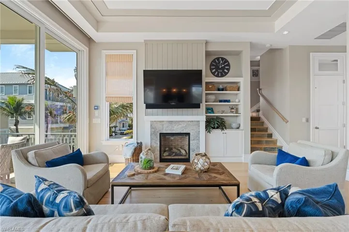Living area with baseboards, stairs, a premium fireplace, built in shelves, and wood finished floors
