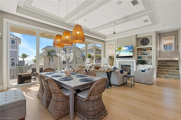 Dining room with a tray ceiling, light wood-style floors, and visible vents