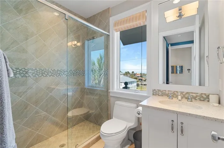 Full bath with toilet, tasteful backsplash, vanity, and a stall shower