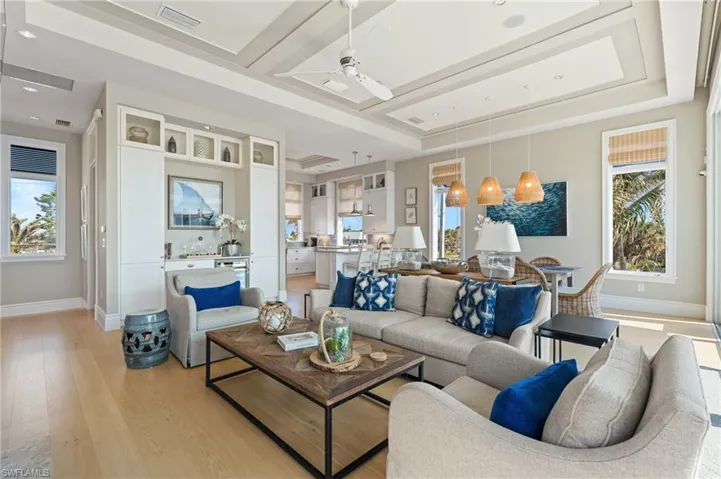 Living area featuring ceiling fan, a tray ceiling, light wood-type flooring, visible vents, and baseboards