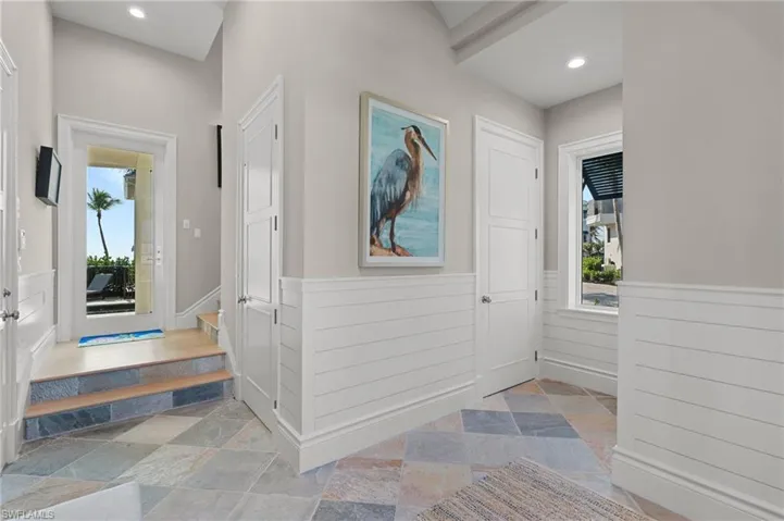 Foyer entrance featuring recessed lighting, stone tile flooring, and a wainscoted wall