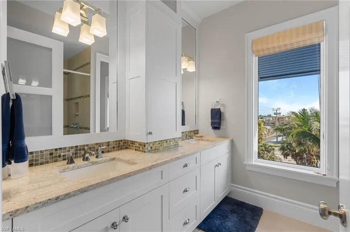 Primary Bathroom with a shower stall, double vanity, decorative backsplash, and a sink
