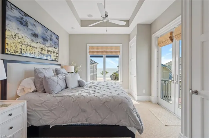 Bedroom with baseboards, access to outside, a tray ceiling, and light colored carpet