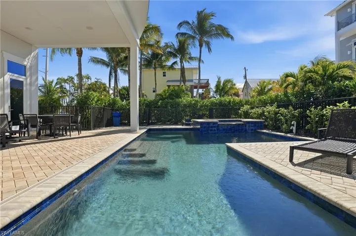 View of pool with a patio, a pool with connected hot tub, outdoor dining space, and a fenced backyard